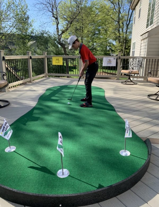 Golfer practicing putts on the Big Moss General Putting Green 6x12 outdoor setup with flagsticks - ALLBGT