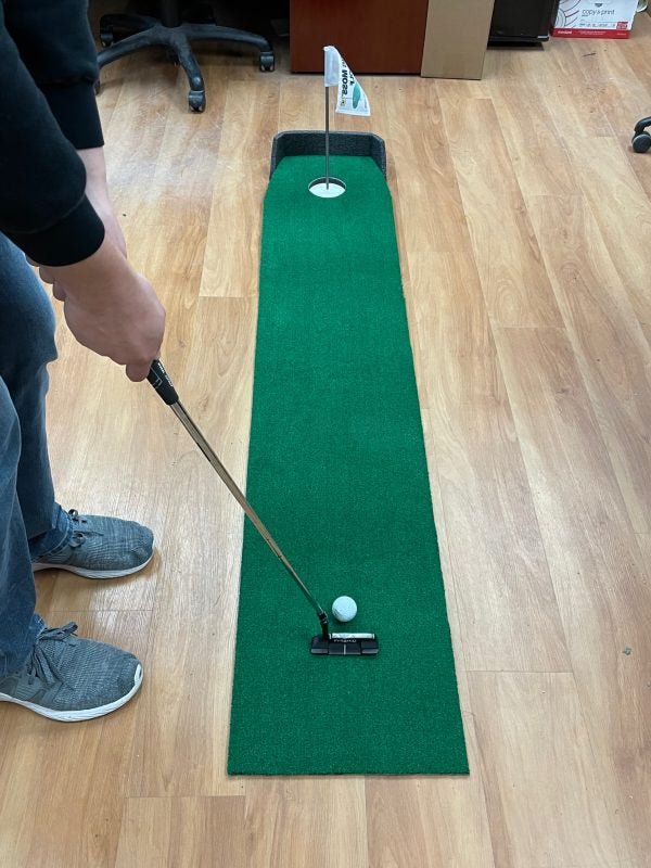 "Golfer practicing short putts on the Big Moss Office Putting Green 6-foot training mat - ALLBGT"
