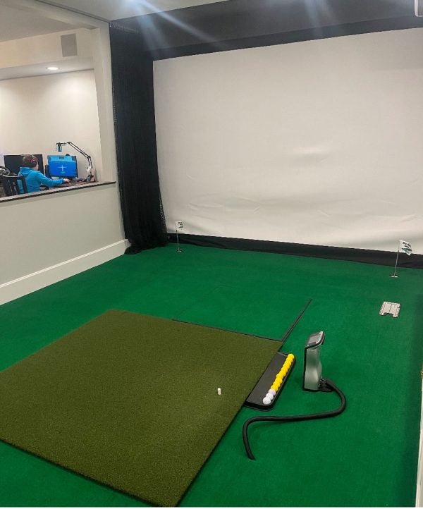 Indoor golf simulator setup featuring Big Moss True Launch PLUS 5'x10' Hitting Mat on green turf - ALLBGT