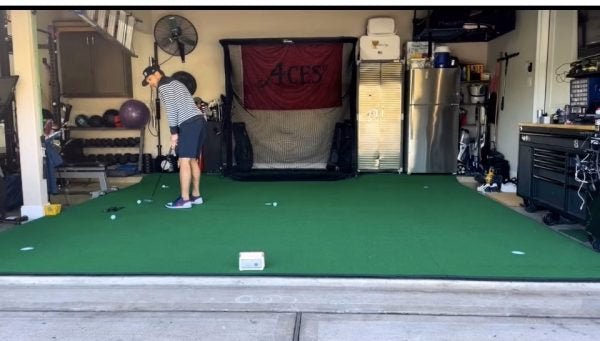 Garage golf practice area featuring Big Moss V2 Bulk Turf putting green and hitting net for training. - ALLBGT