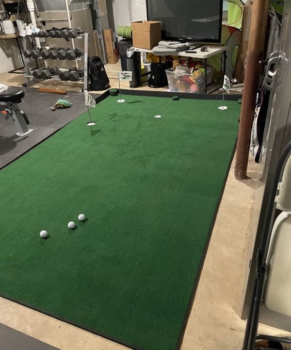 Compact home gym with Big Moss V2 Bulk Turf putting green and practice flags for indoor golf training. - ALLBGT