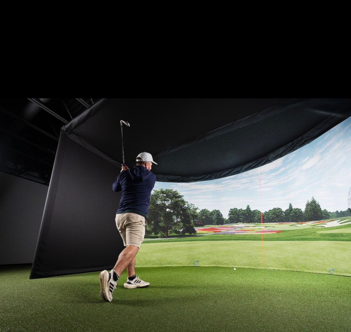 "Indoor setup of Carl’s Place Curved Golf Simulator Enclosure Kit with showing realistic projected golf course - ALLBGT"