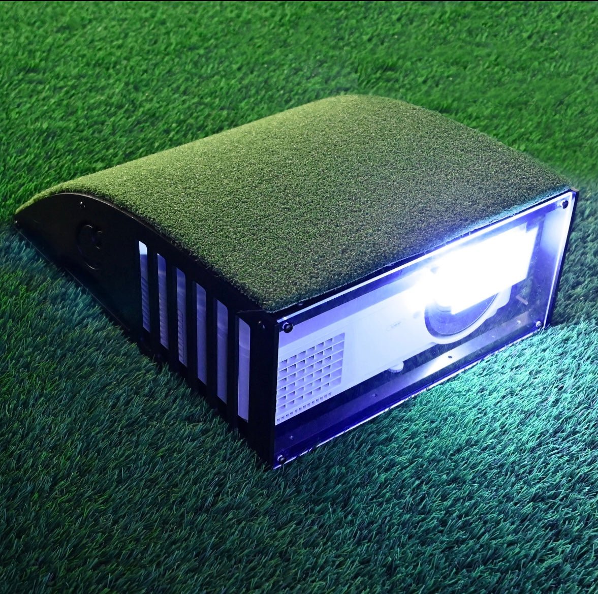 “Carl’s Place Floor-Mounted Projector Enclosure Kit in use with projector light on indoor turf - ALLBGT.”