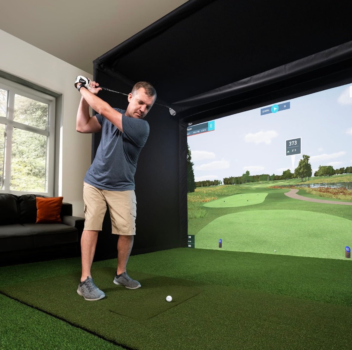 "Golfer practicing in Carl’s Place Pro Golf Simulator Enclosure Kit with realistic indoor golf setup - ALLBGT."
