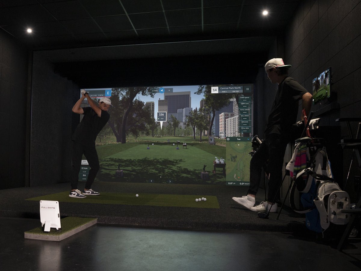 “Two golfers using the Full Swing KIT Golf Launch Monitor in a dark room golf setup - ALLBGT.”