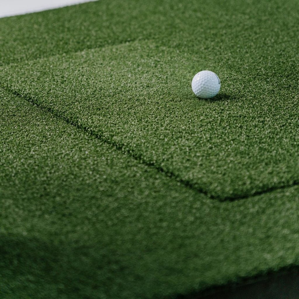 SIGPRO Softy 4x7 Golf Mat close up with golf ball on replaceable hitting strip realistic indoor golf hitting mat turf texture.