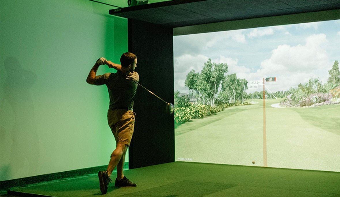 “Golfer practicing indoors with SimBooth 1 Golf Simulator Enclosure and projected virtual fairway - ALLBGT”