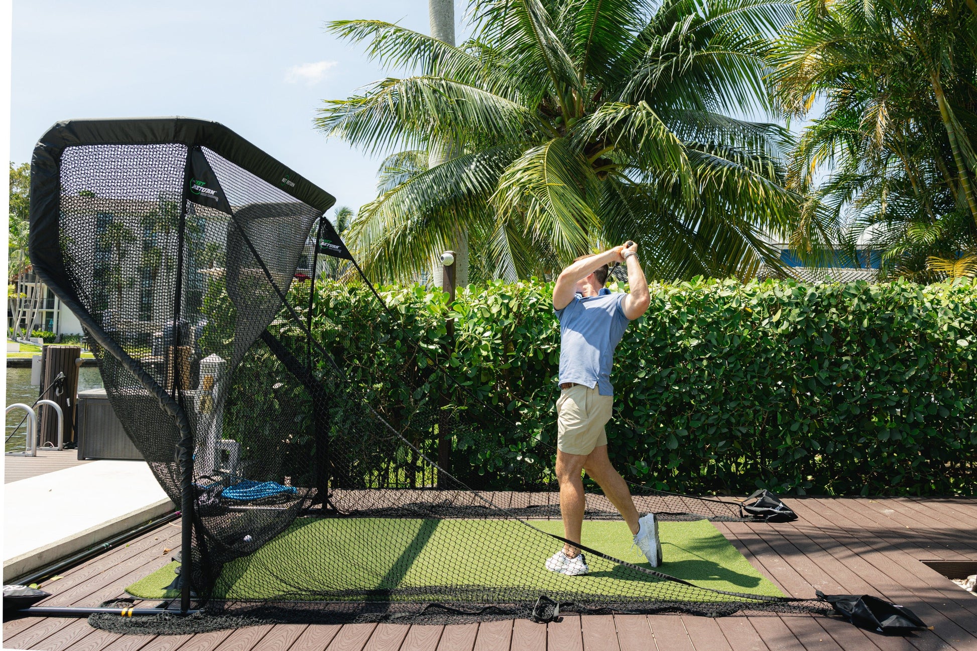 “Golfer practicing outdoors using The Net Return Mini Package with golf mat and net setup - ALLBGT.”