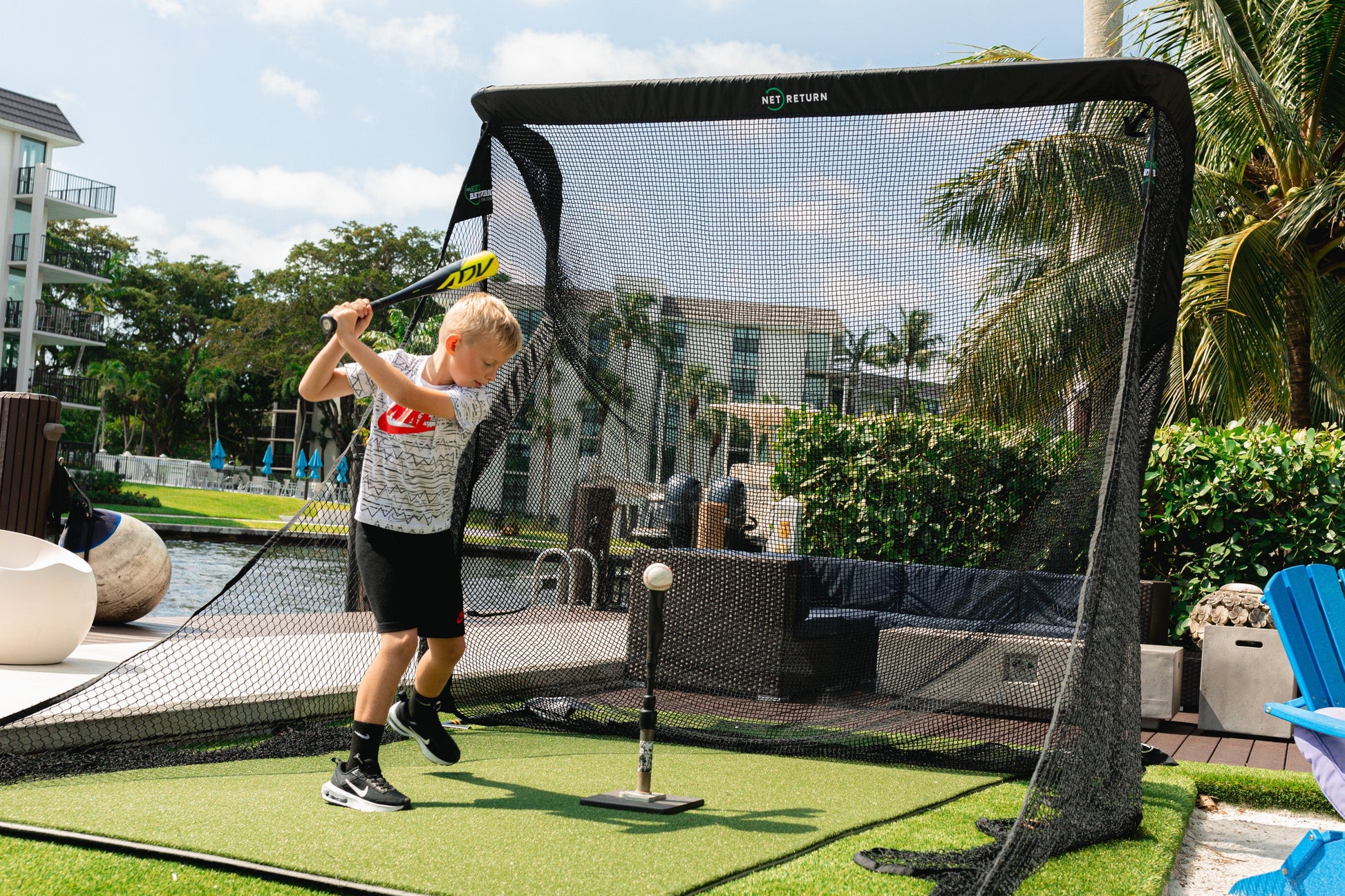 “Child practicing baseball swings with The Net Return Pro Package - Pro Series setup on turf mat - ALLBGT.”