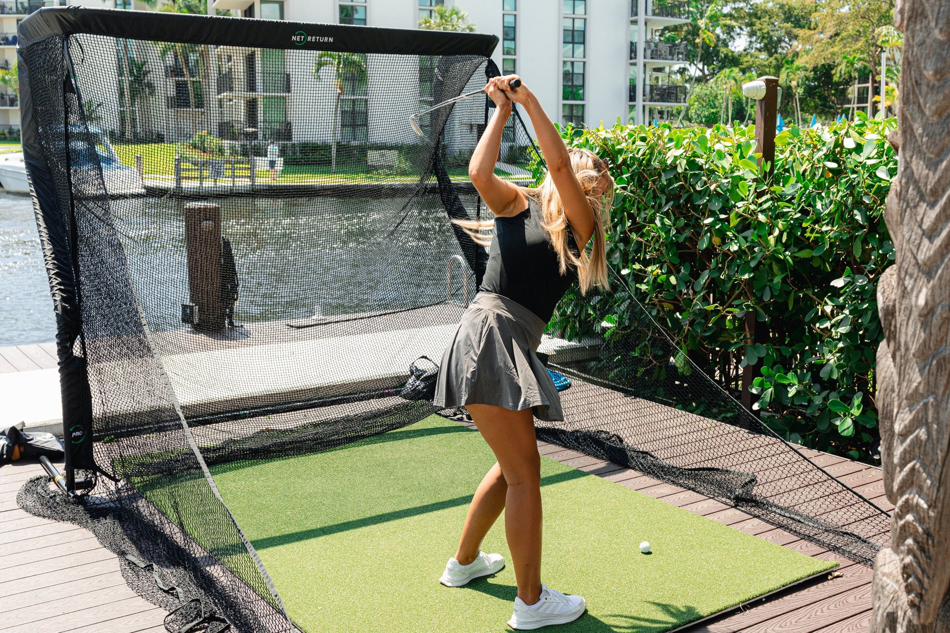 Golfer practicing with The Net Return Pro Package - Pro Series Golf net setup outdoors on Pro turf mat - ALLBGT