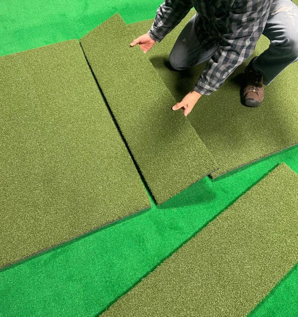 "Golfer assembling the Big Moss True Launch Hitting Strip 12x4 ft Reversible Golf Mat on the floor setup - ALLBGT"