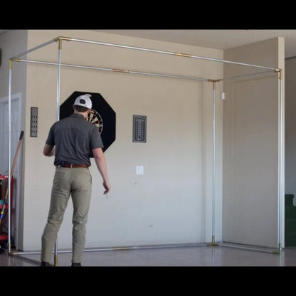 Person setting up SIG DIY golf simulator enclosure frame setup using EMT pipe frame kit in garage - ALLBGT